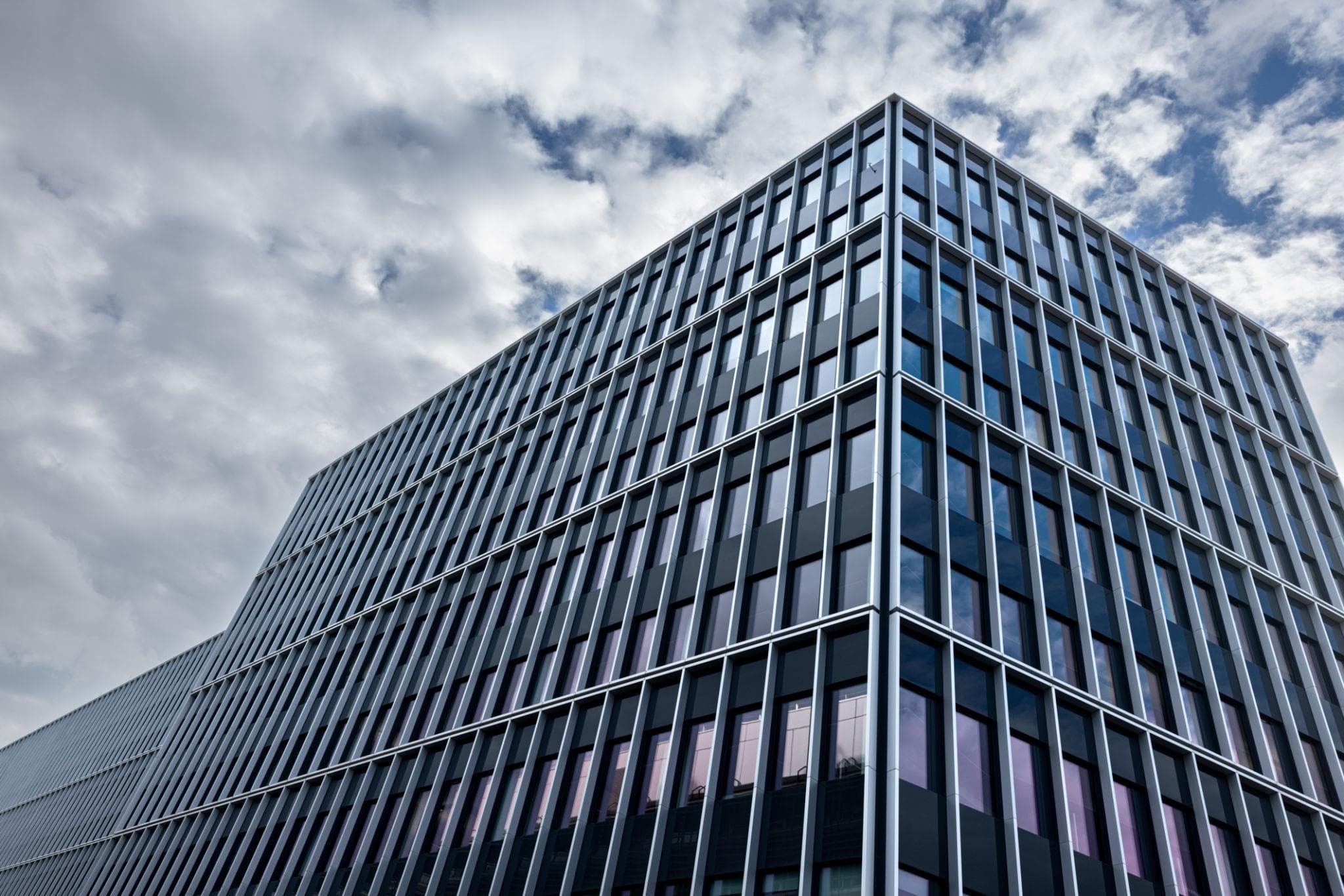 Gebäudeecke eines verglasten Bürogebäudes mit regelmässigem Fensterraster, bedeckter Himmel.